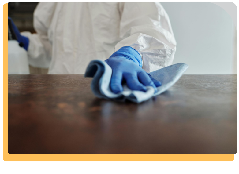 person in gloves wiping down a wooden surface with a rag