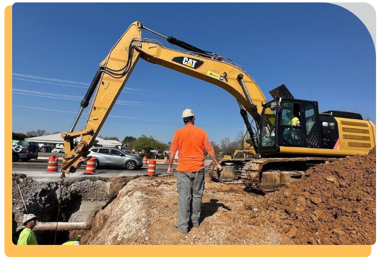 a man supervising as another worker operates a bulldozer digging a hole