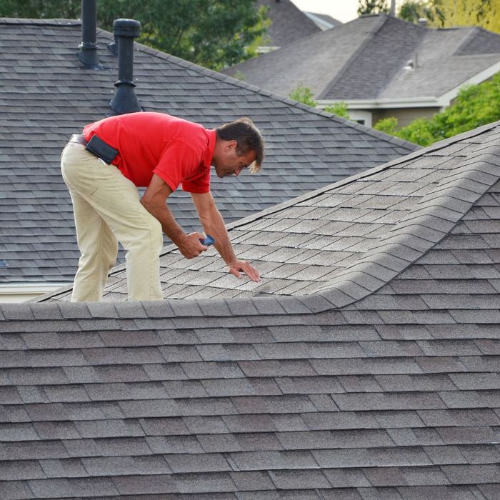 roofer inspecting shingles on roof