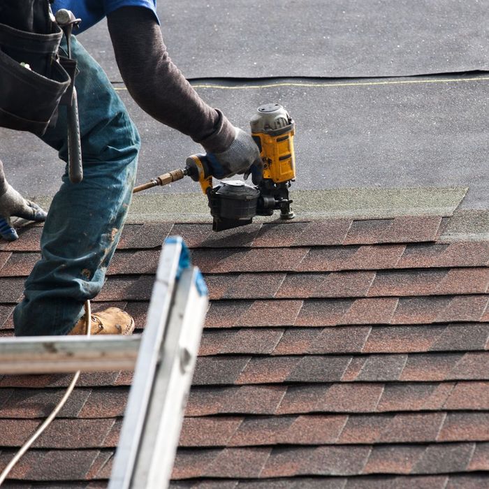 A person installing shingles on a roof