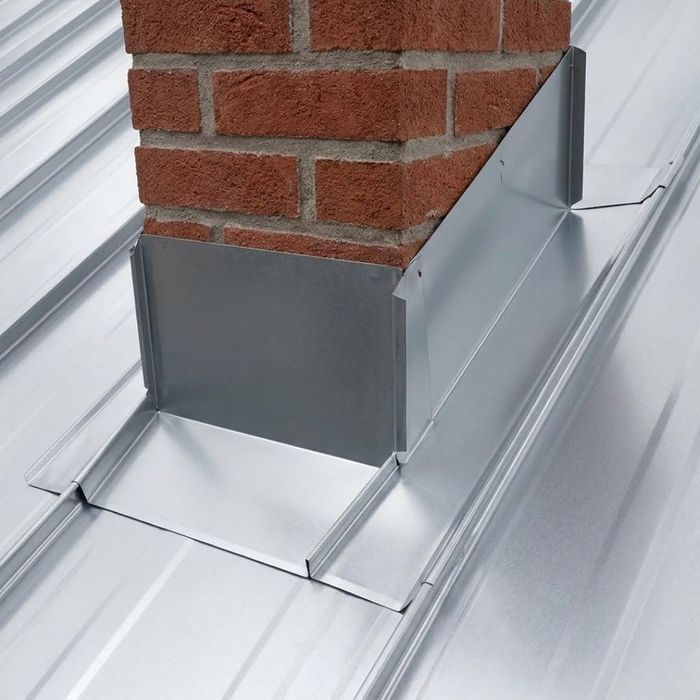 A detailed close-up shot showing metal flashing layered correctly around the base of a brick chimney.