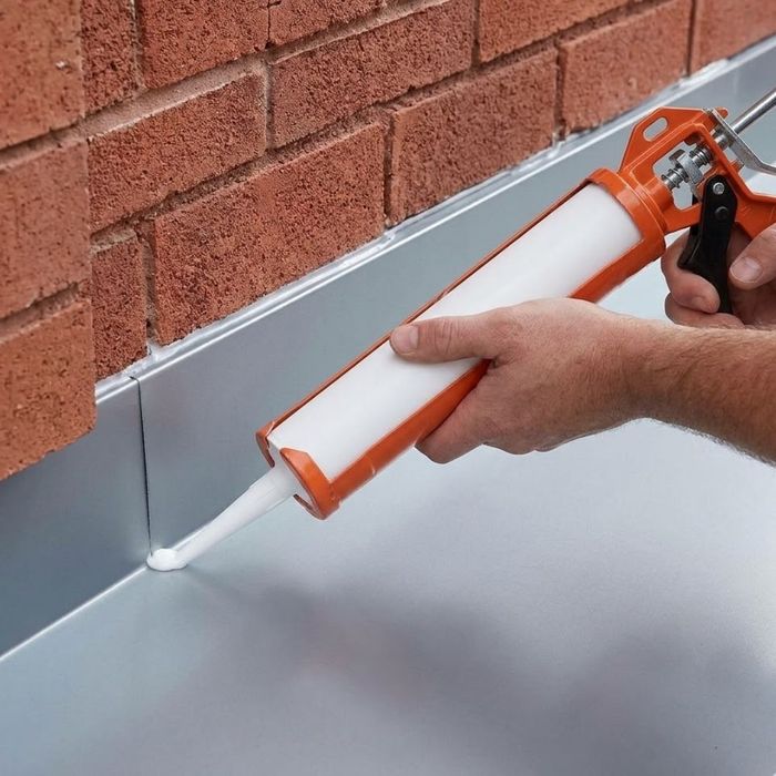 Hand using caulk gun to seal flashing.