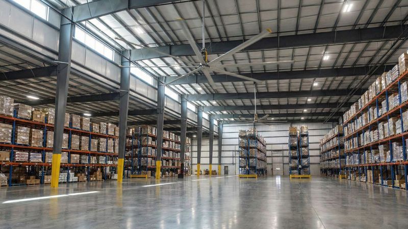 Wide shot of a modern Texas warehouse interior featuring large HVLS ceiling fans and dry polished concrete floors.