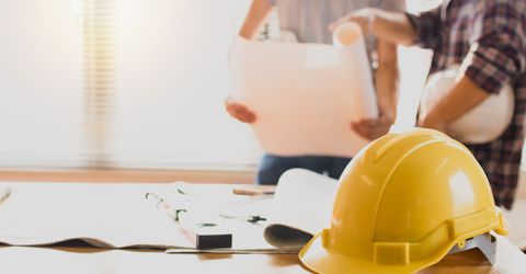 hard hat with workers going over plans