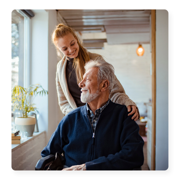 A older man being pushed in a wheelchair by his smiling daughter