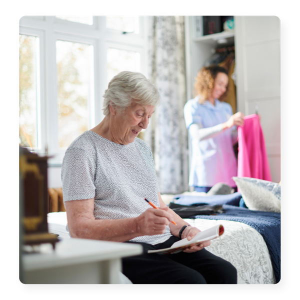 A happy senior woman playing a crossword in her room