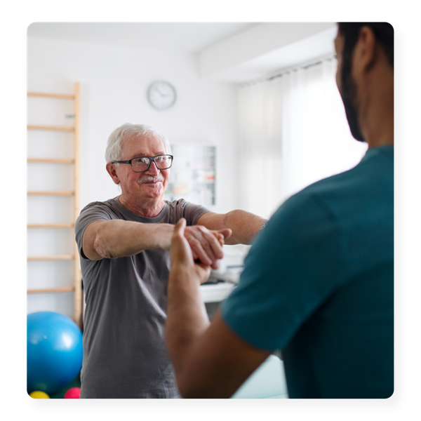 A older man in glasses doing exercises with a physical therapist
