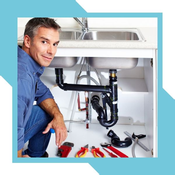 Man smiling with a sink repair in the background