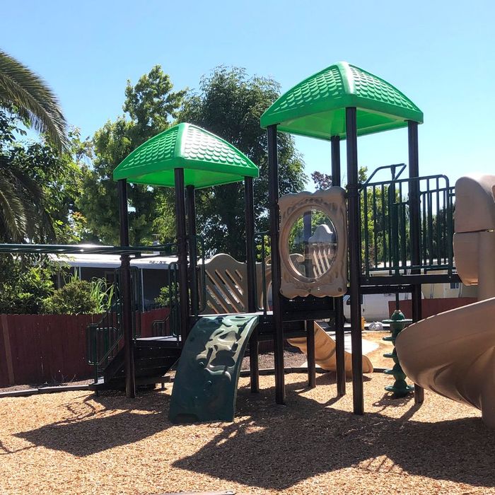 A playground with a play structure featuring two green, peaked roofs. A playground with a play structure featuring two green, peaked roofs.