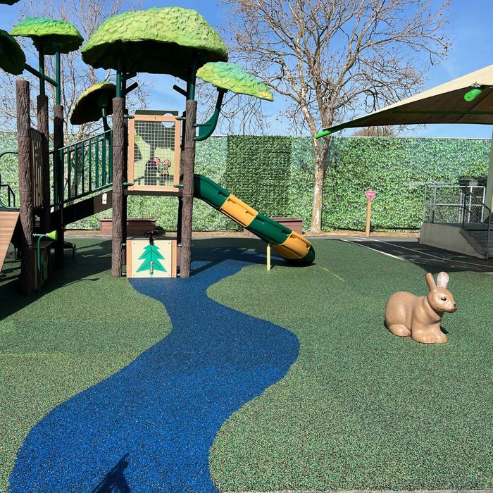 A playground with a green and brown play structure designed to look like a tree, complete with leafy canopies. A playground with a green and brown play structure designed to look like a tree, complete with leafy canopies.