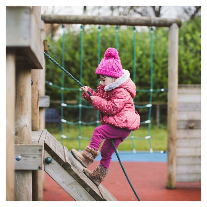 toddler climbing up wall with rope 