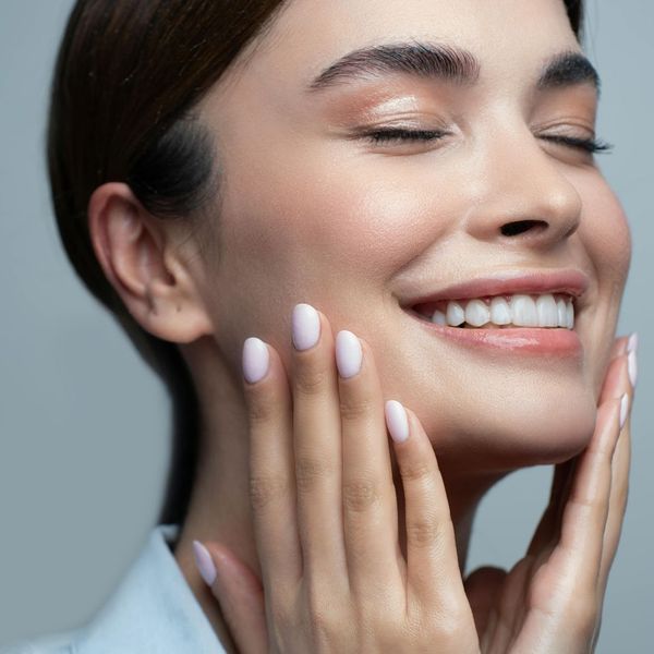woman smiling holding face with beautiful skin