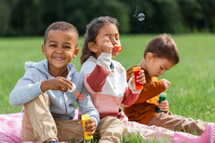 childhood, leisure and people concept - group of children blowing soap bubbles at park.png