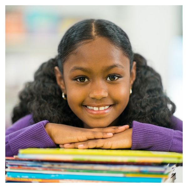 smiling girl resting chin on stack of books