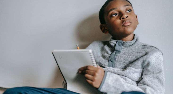 little boy holding notebook looking off in the distance