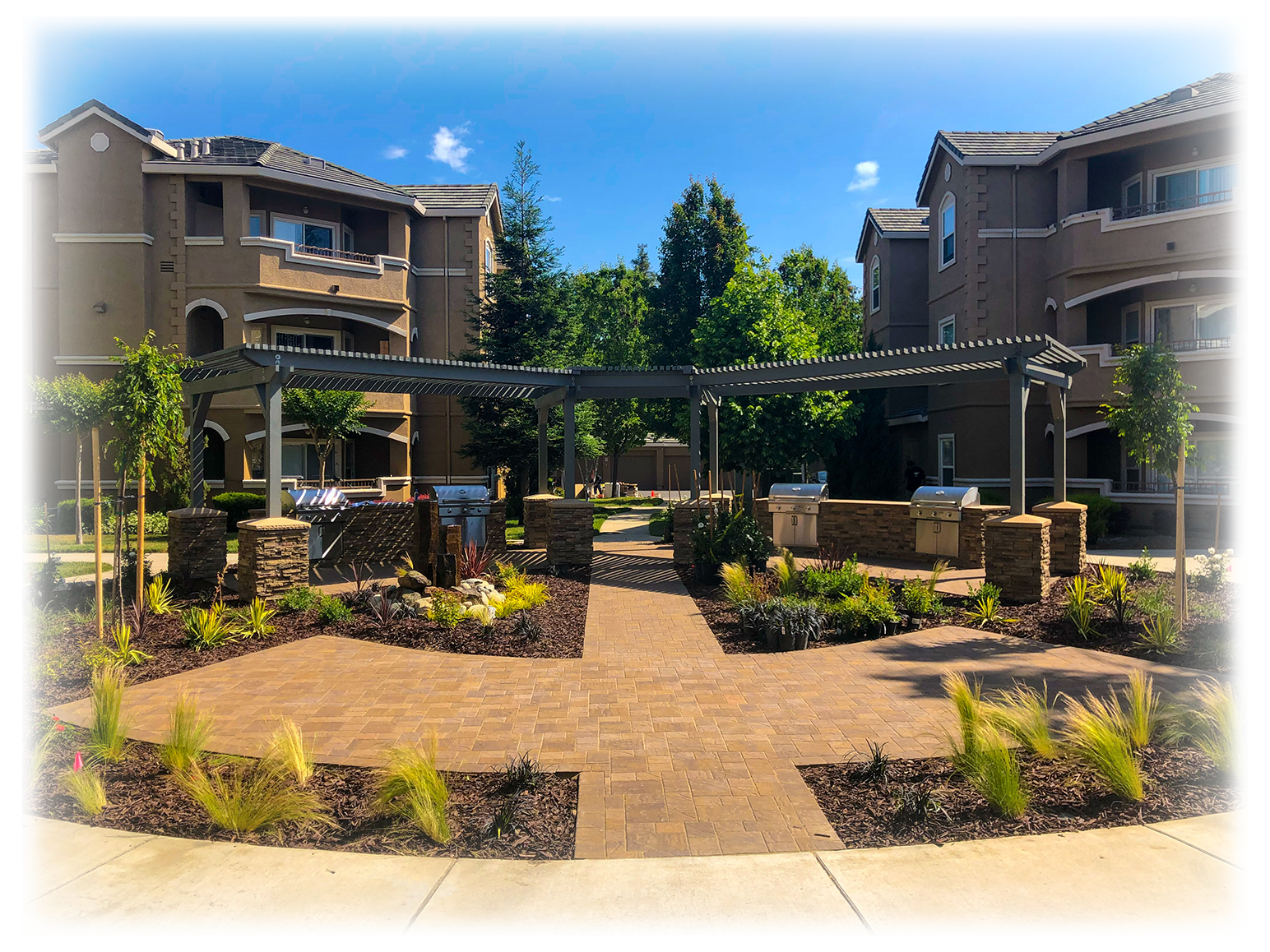 two big homes with big landscape infront of them, with two patios and pavers in addition to plants all over Landscaping