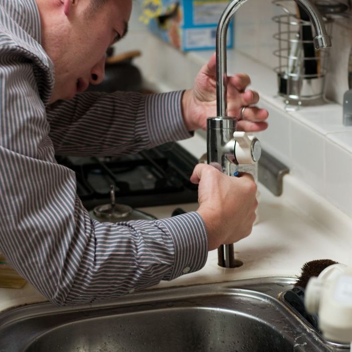person installing faucet to kitchen sink