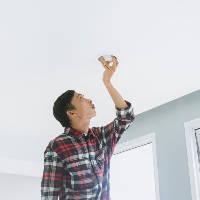 person installing lightbulb in ceiling