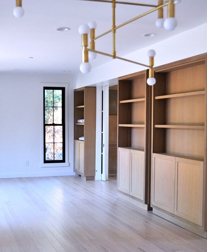 a newly designed living room with shelves and a chandelier