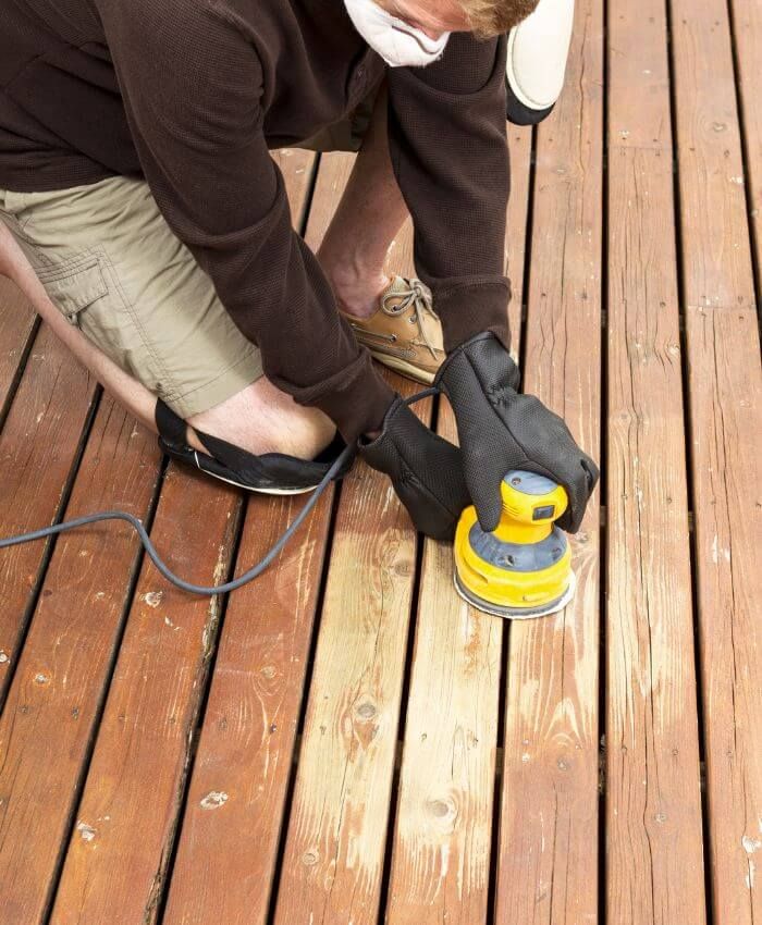 person sanding wooden deck