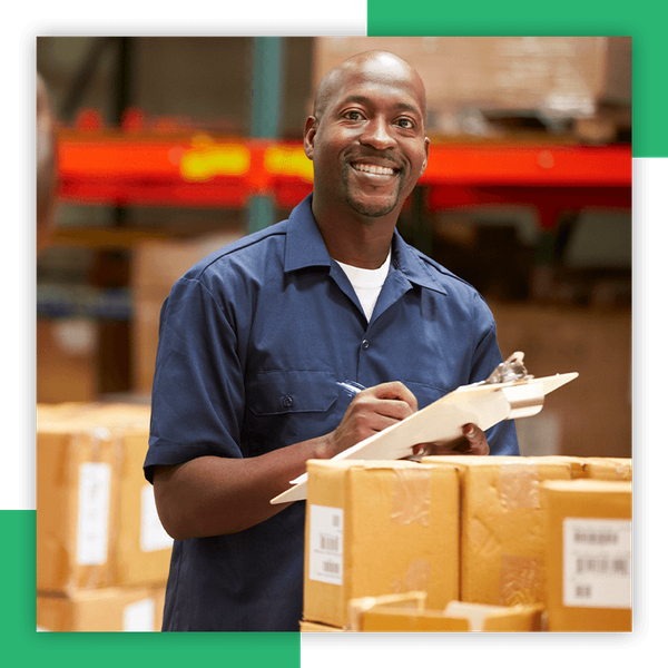 A warehouse employee writing information on a clipboard