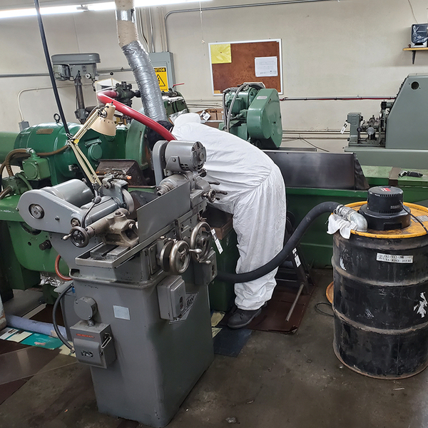worker cleaning around a manufacturing machine