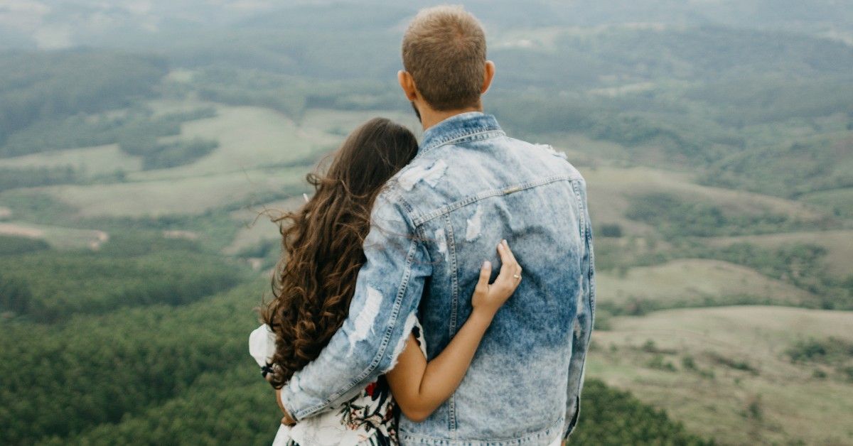 Couple standing on the edge of mountainside looking in the distance