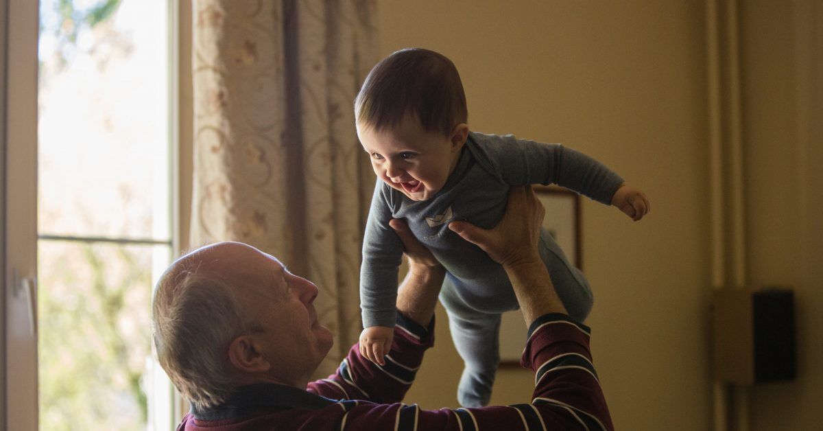 Grandparent lifting happy baby into the air