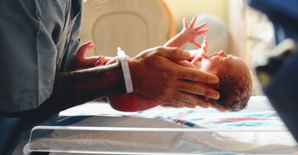 in delivery room, holding newborn baby