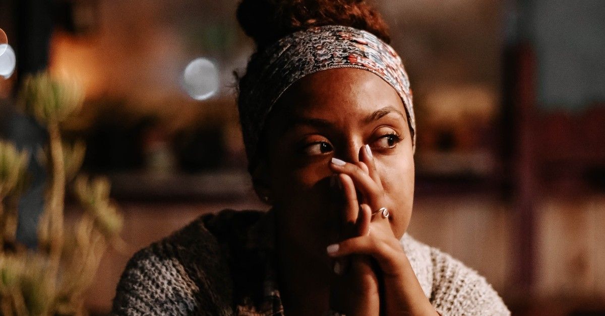 contemplative woman looking off camera with hands covering her mouth and nose