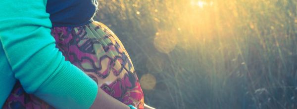 closeup of pregnant woman's belly in a grass field