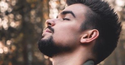 man outdoors eyes closed with head raised to the sky