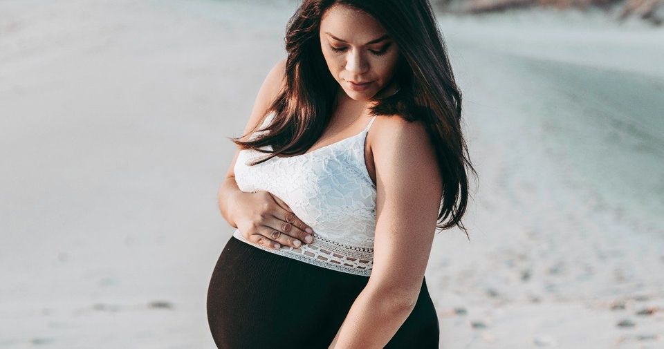 pregnant woman on the beach wearing a dress