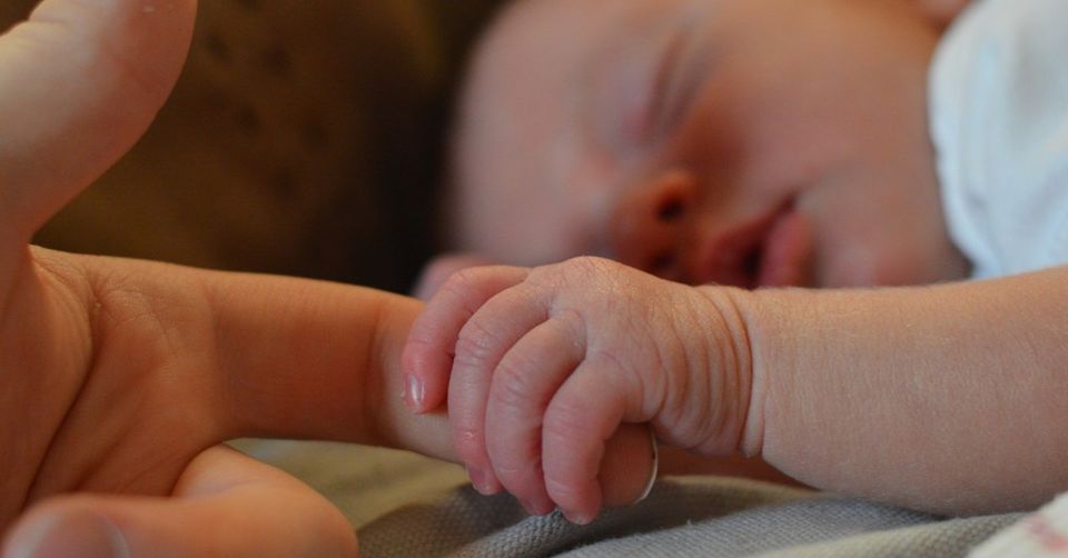 newborn wrapping finger around parent's finger