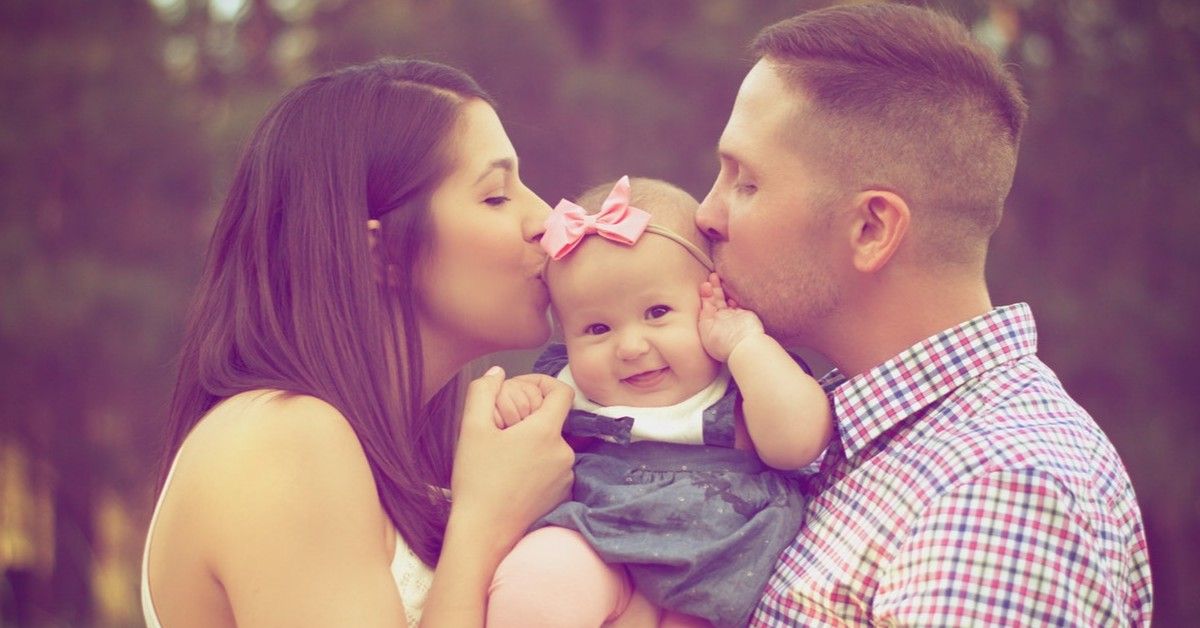 couple kissing their little baby girl