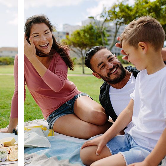 Couple sitting in park laughing with their young boy