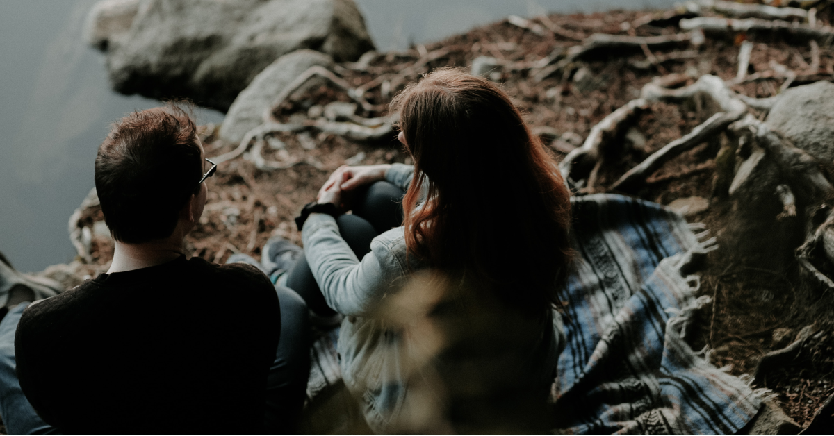 couple sitting at the edge of a lake