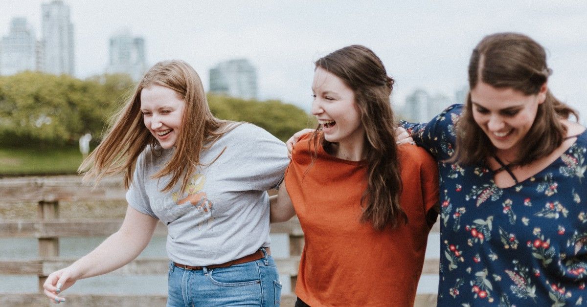 group of girls laughing outdoors, city landscape in background