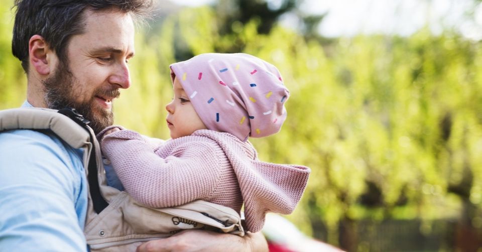 man smiling with baby girl outdoors