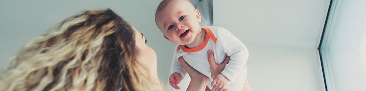 woman playfully lifting happy baby in the air