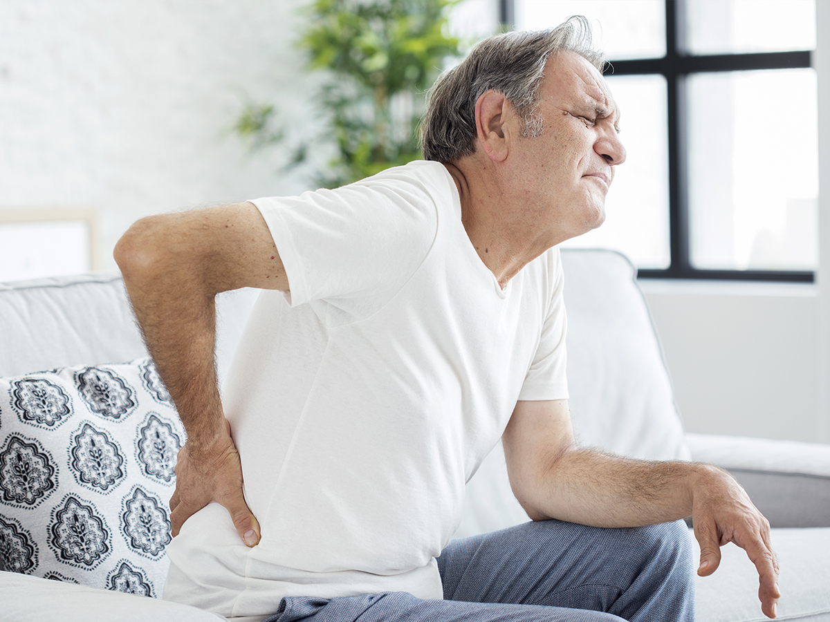 Image of an older man holding his lower back in pain Image of an older man holding his lower back in pain