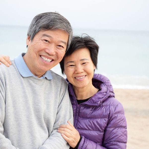 elderly man and woman smiling on the beach