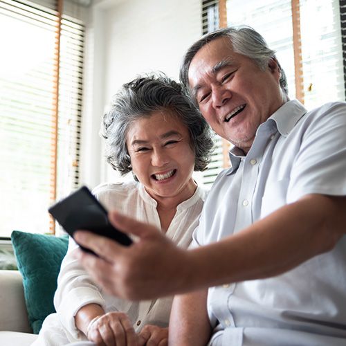 gray-haired couple smiling looking at a phone