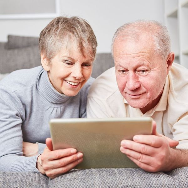 elderly man and woman smiling at a tablet