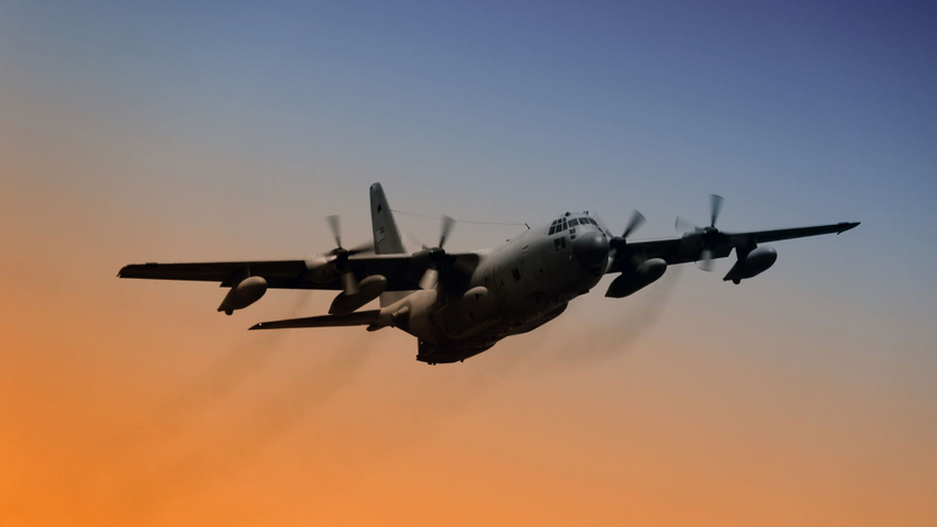 military aircraft flying at sunset