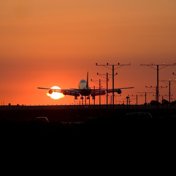 airplane taking off at sunset with landing gear still deployed