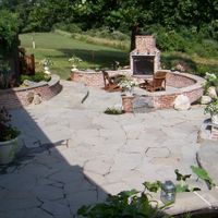 a stone patio with a fireplace