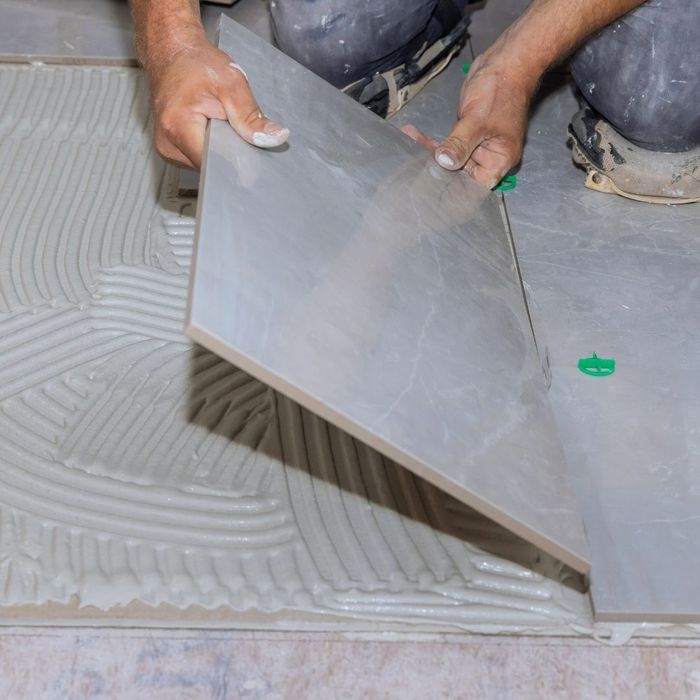 Worker precisely installing bathroom floor tile
