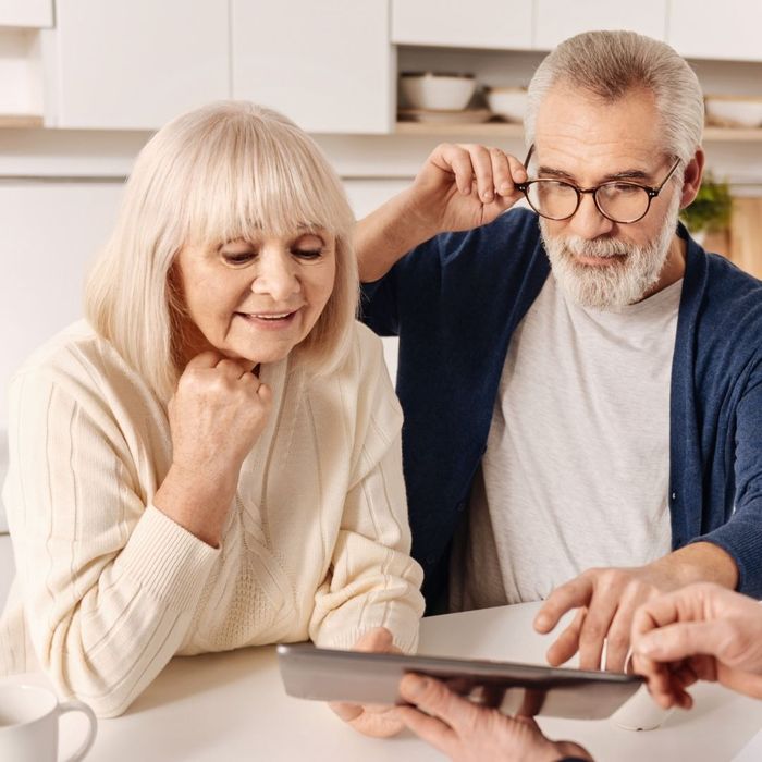 A happy couple discussing kitchen renovation costs with a friendly contractor, who is showing transparent pricing on a tablet.
