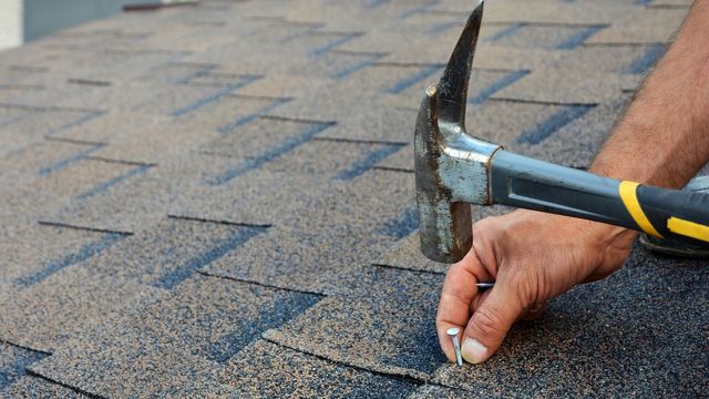 person putting a nail ina roof